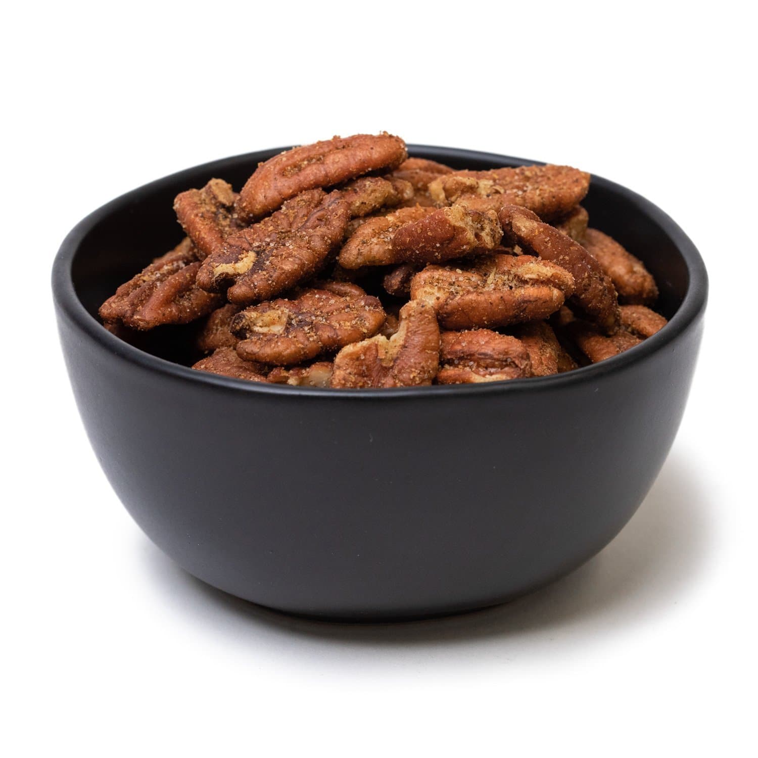 A black bowl filled with Green Chile pecans on a white background.
