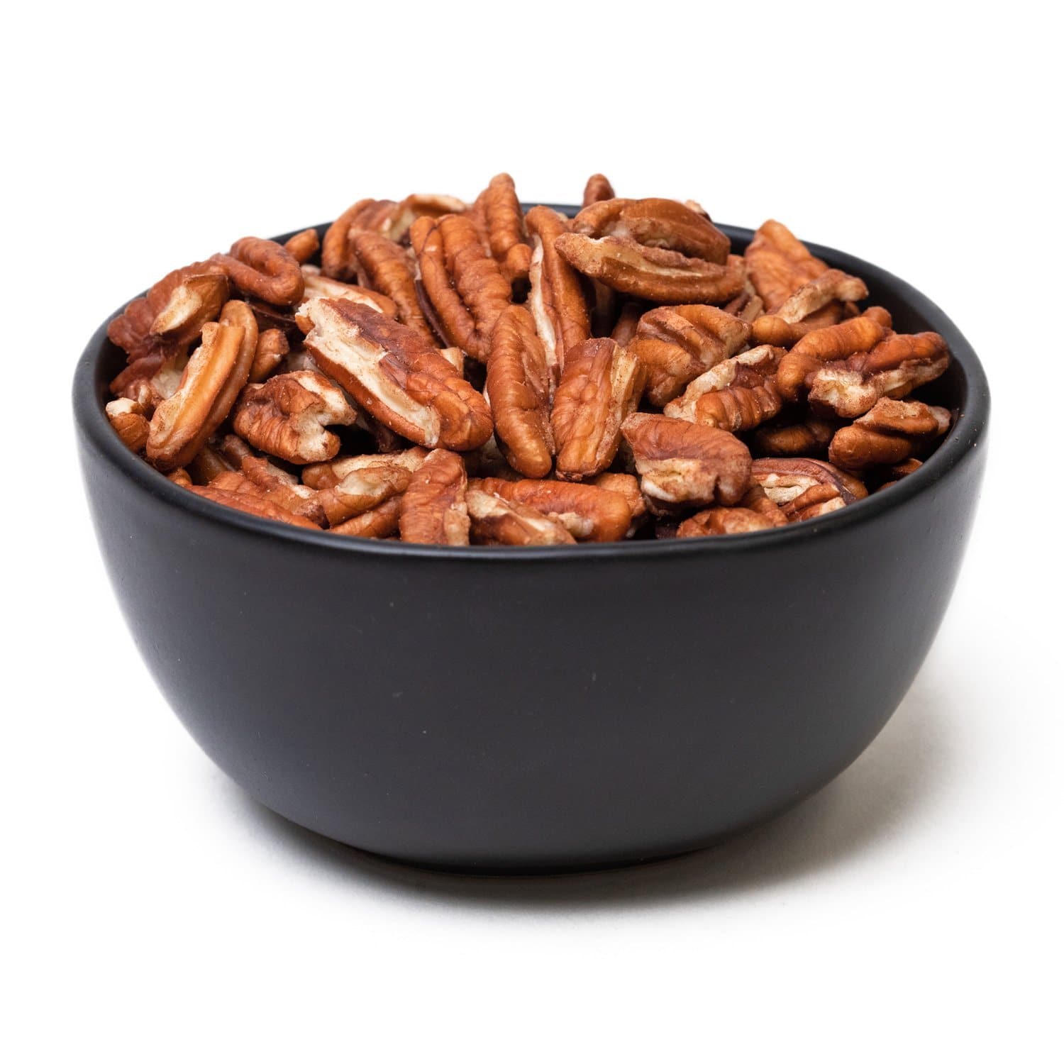 A black bowl filled with brown California grown pecan pieces against a white background.