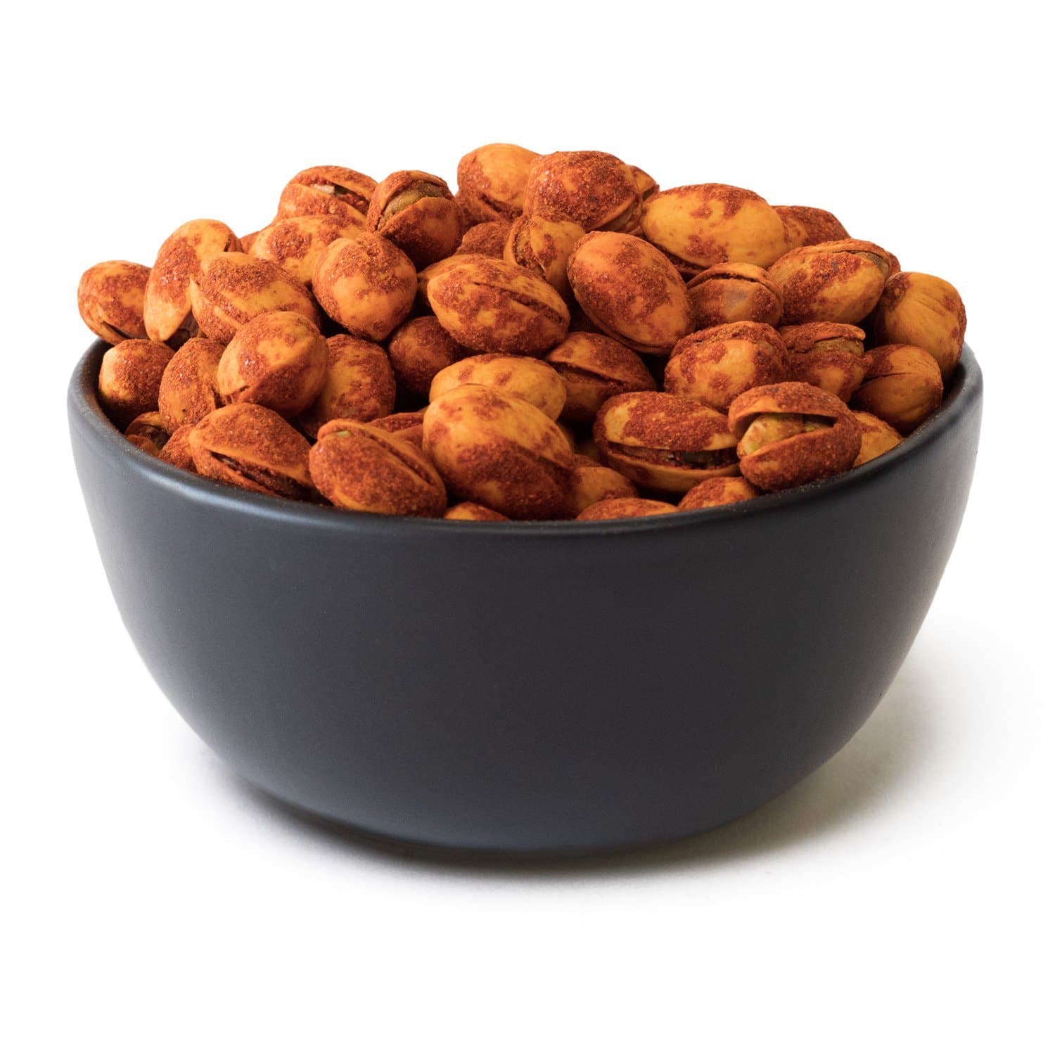 A bowl of Red Chile Pistachios coated with a spicy seasoning, isolated on a white background.