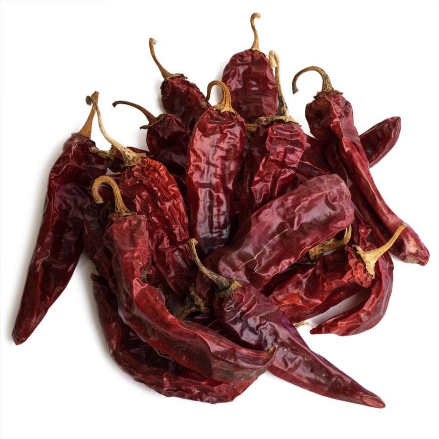 A pile of traditional sun-dried Sun-Dried Red Chile Sauce peppers with intact stems, positioned against a white background. The peppers vary slightly in shape and texture, showing natural wrinkles.