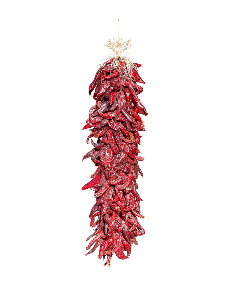 A Traditional Sandia Ristra, which is a hanging decoration made of numerous bright red chili peppers, against a white background.